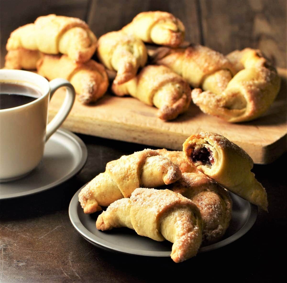 Side view of Polish rogaliki crescent cookies on saucer and wooden board.
