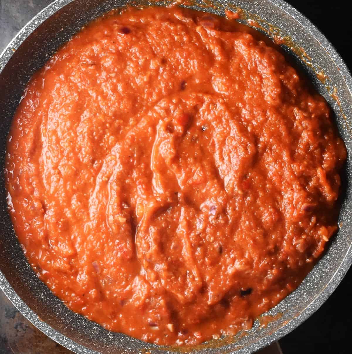 Top down view of thick tomato pepper sauce in large pan.
