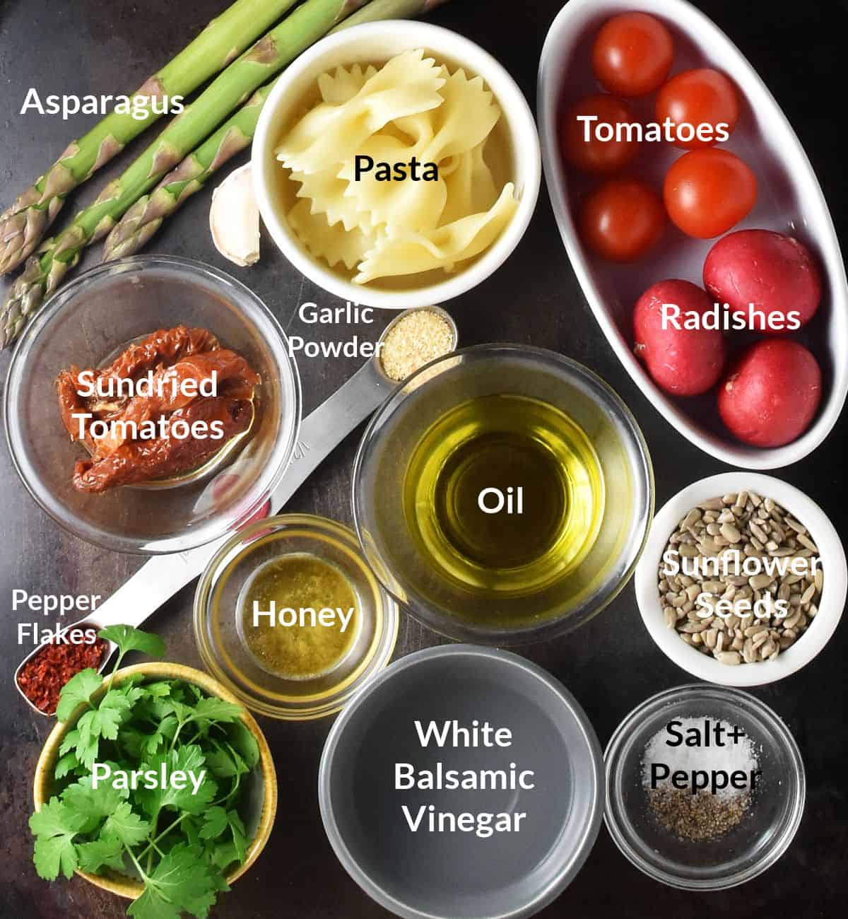 Top down view of ingredients for asparagus pasta salad in individual, different colour dishes.
