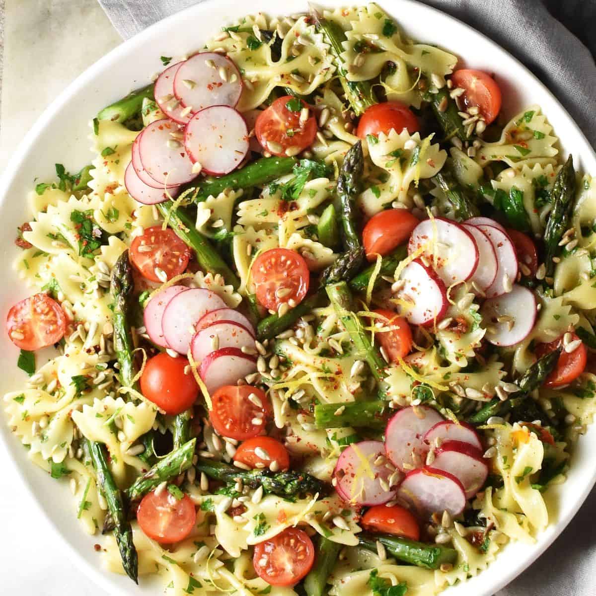 Top down view of asparagus pasta salad on large white plate.