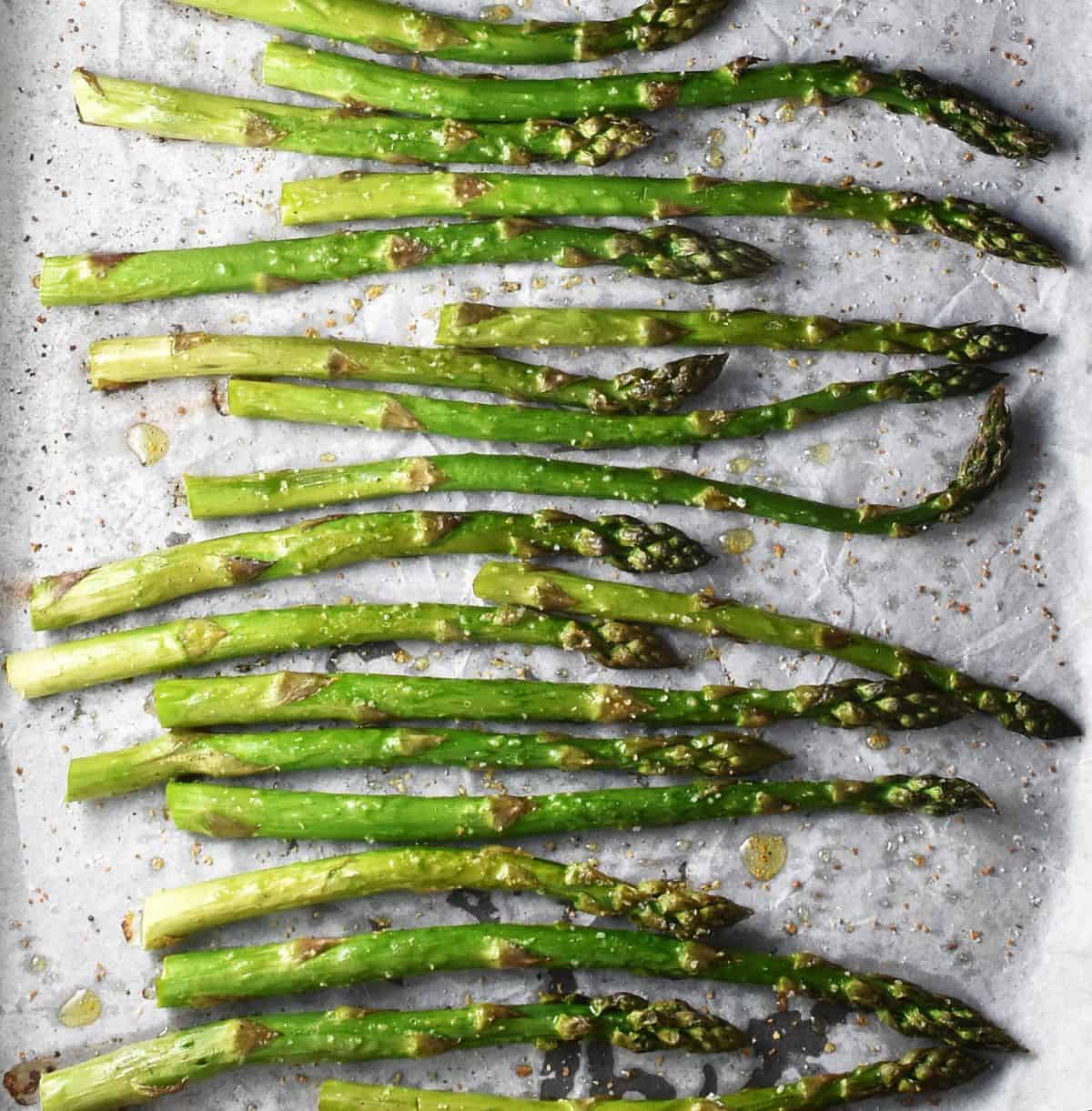 Top down view of roasted asparagus tips on parchment.