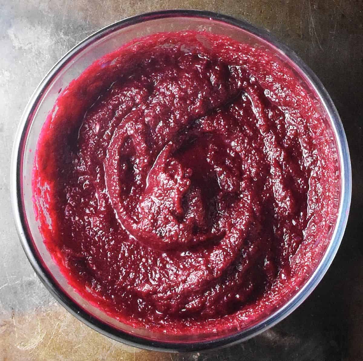 Top down view of beet mixture puree in glass bowl.