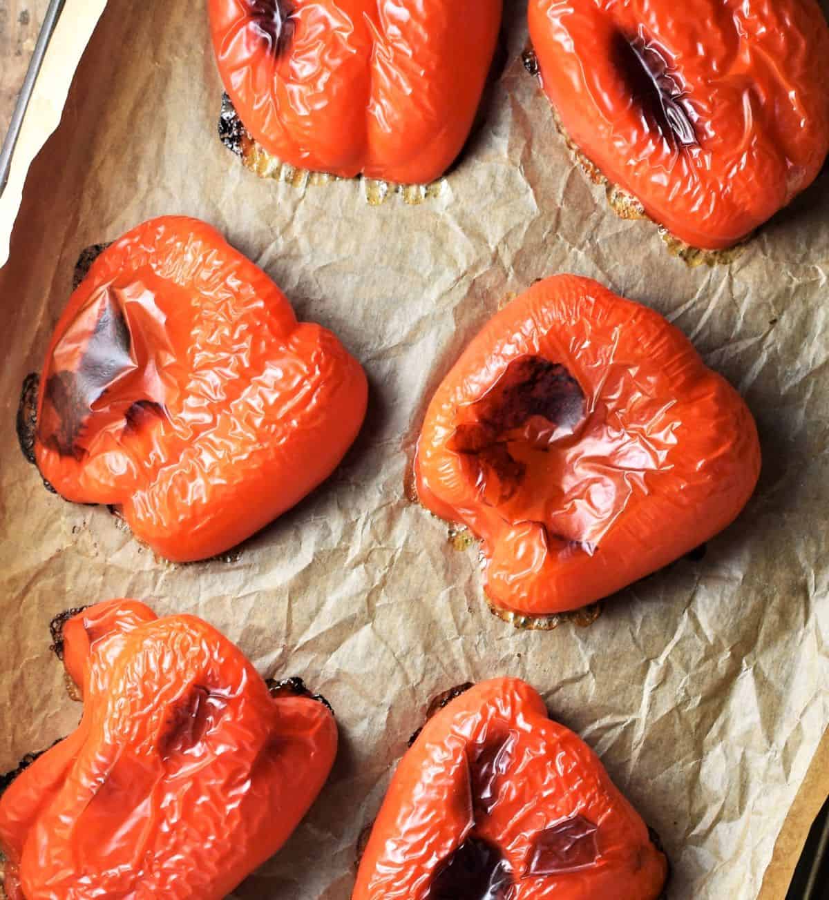 Top down view of roasted red pepper halves on parchment.