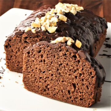 Side view of gingerbread loaf cake topped with chocolate and nuts.