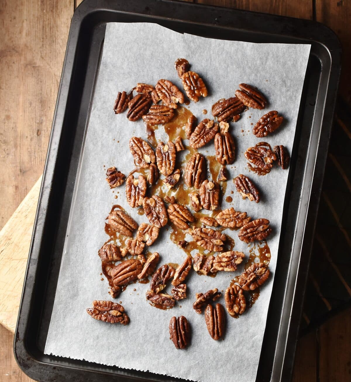 Roasted pecans on top of baking sheet lined with parchment paper.