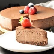 Side view of chocolate ricotta cheesecake slice on plate with cheesecake in background.
