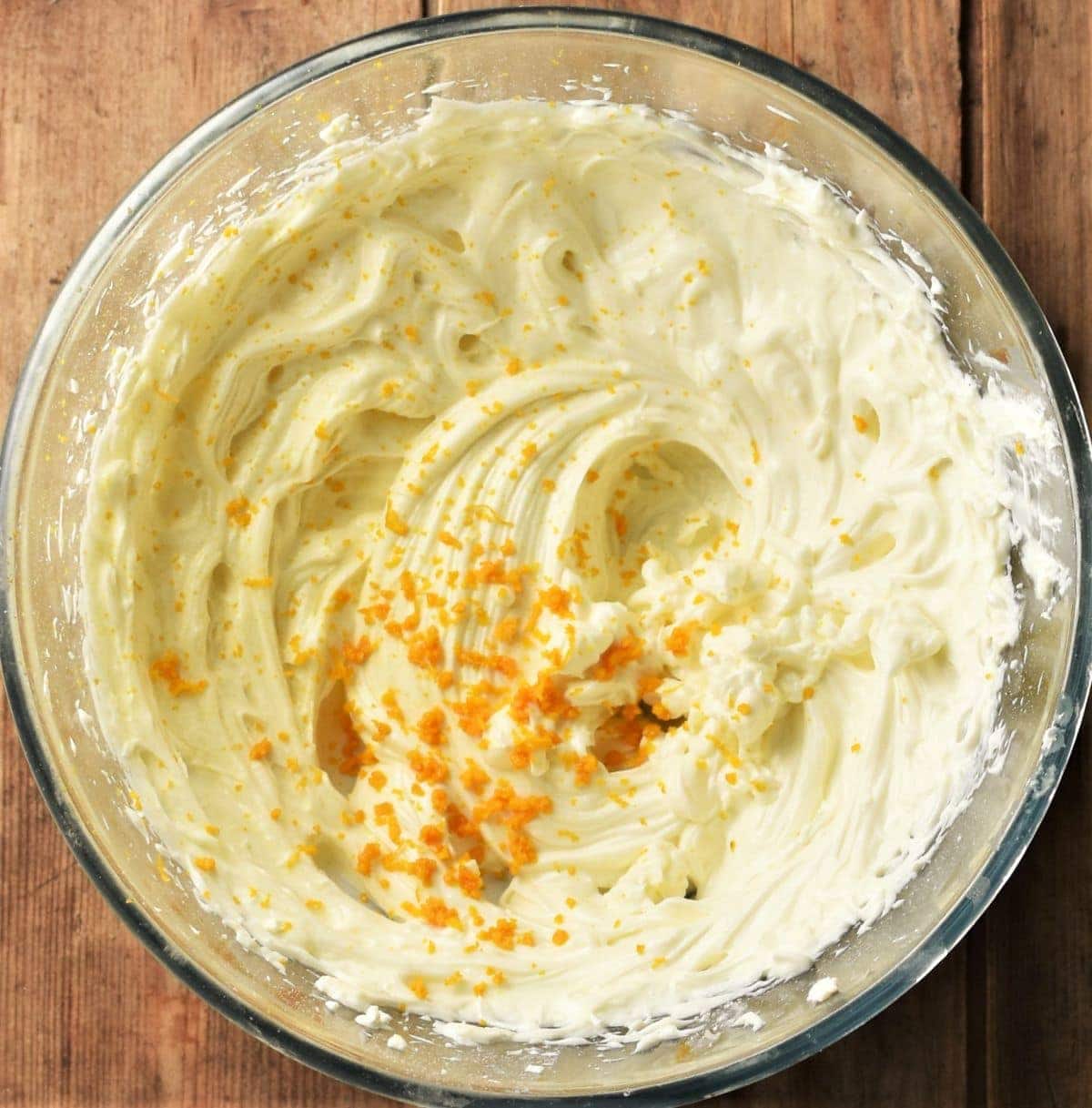 Frosting mixture with orange zest in bowl.