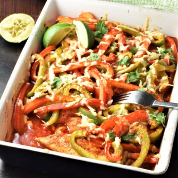 Side view of chicken fajita casserole with fork and lime in background.