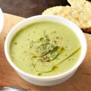 Side view of creamy brussels sprout soup in white bowl.