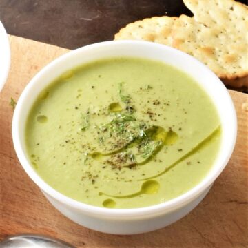 Side view of creamy brussels sprout soup in white bowl.