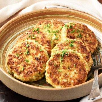 Side view of fried egg patties in brown bowl.