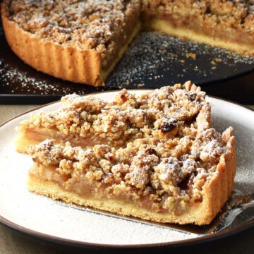Side view of apple crumble tart slices on white plate.