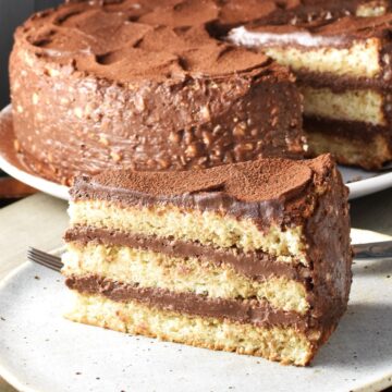 Side view of Polish hazelnut torte torte slice on plate with cake in background.
