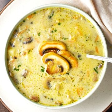 Top down view of Polish mushroom soup in white bowl with spoon.