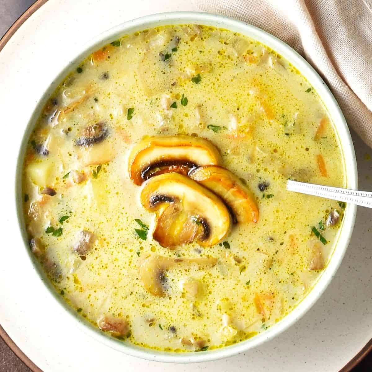 Top down view of Polish mushroom soup in white bowl with spoon.